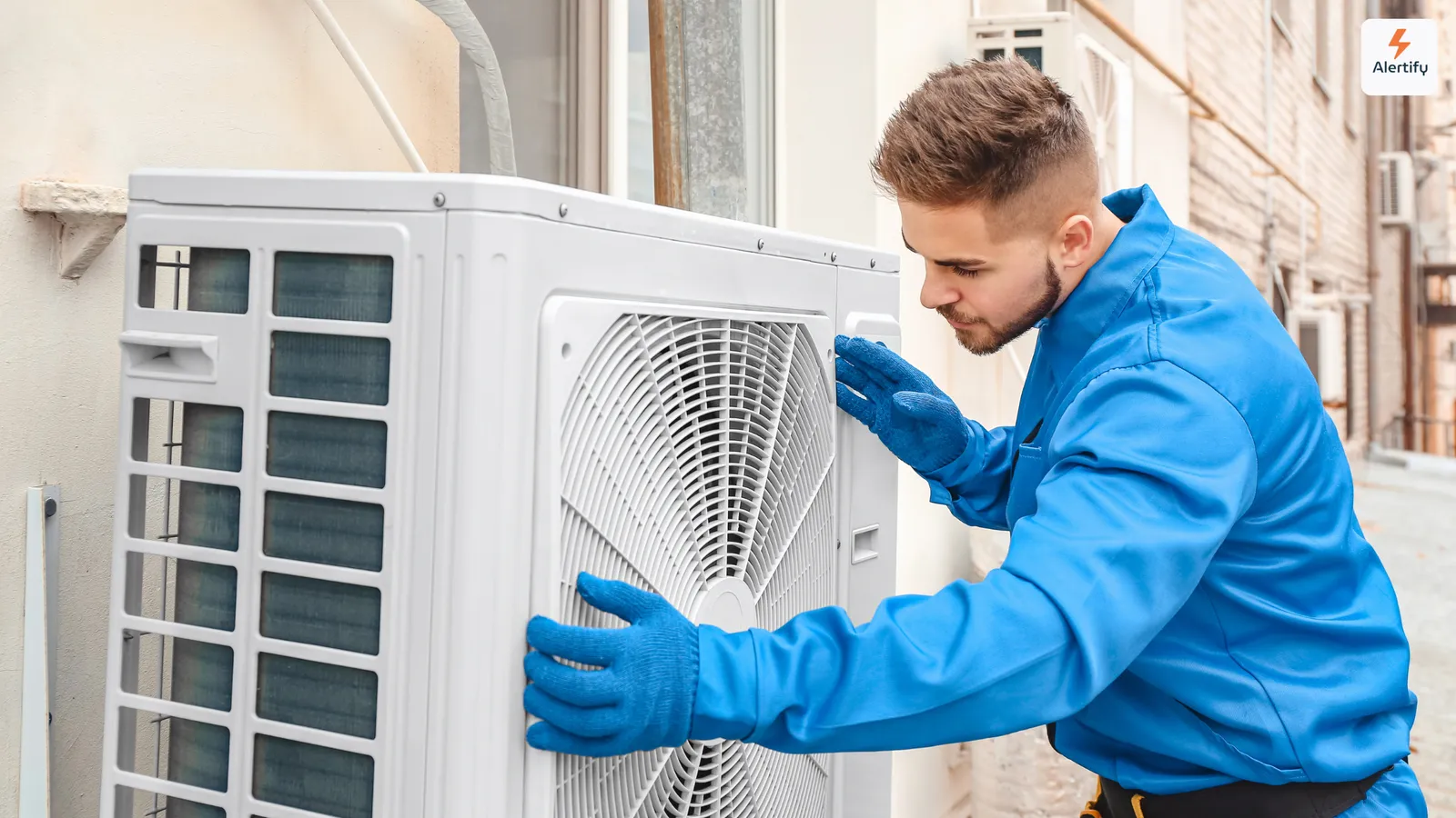 HVAC-monteur in blauwe overall en met handschoenen die een buitenunit van een airconditioning onderhoudt
