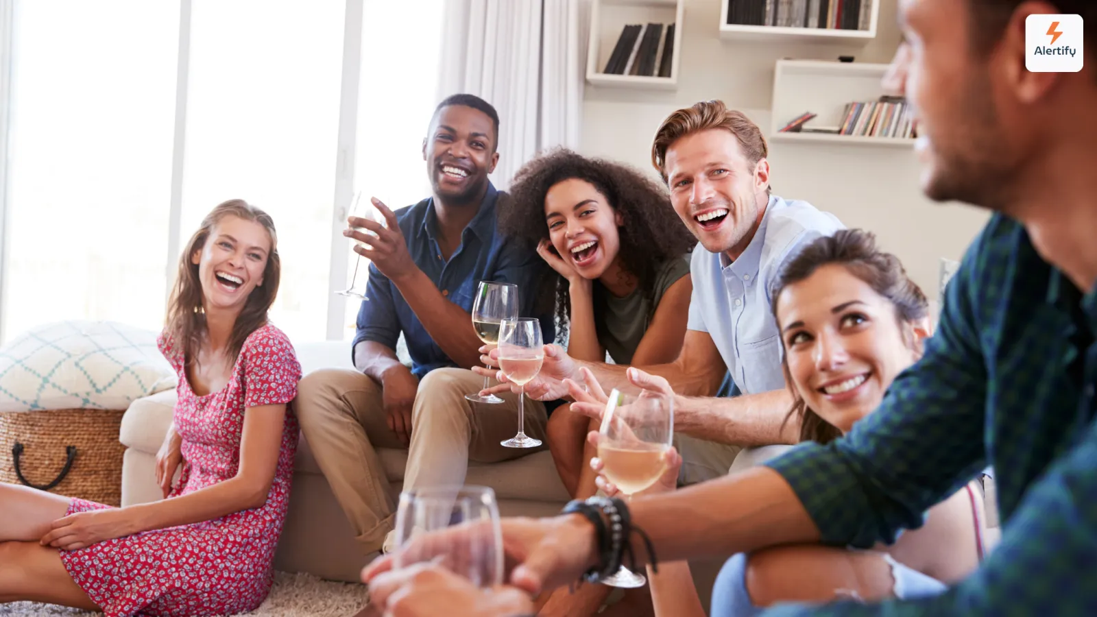 Groep vrienden die lachend een glas wijn drinken in een woonkamer van een vakantiewoning